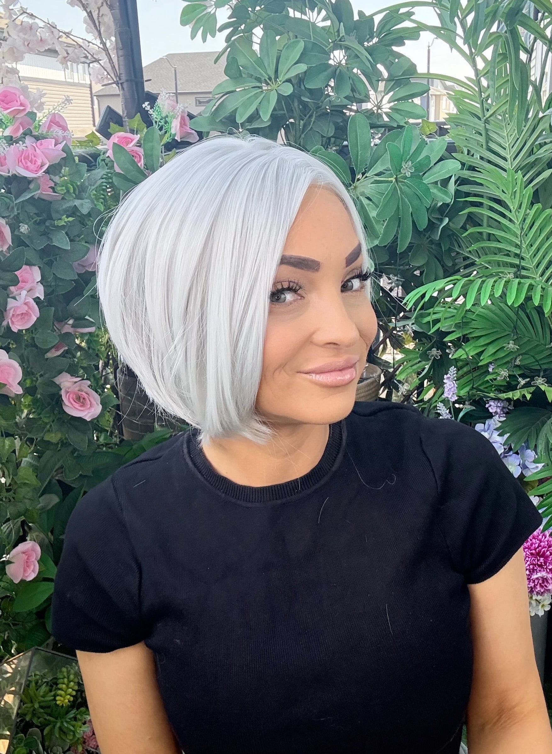 Woman with a stylish haircut standing in front of greenery and flowers