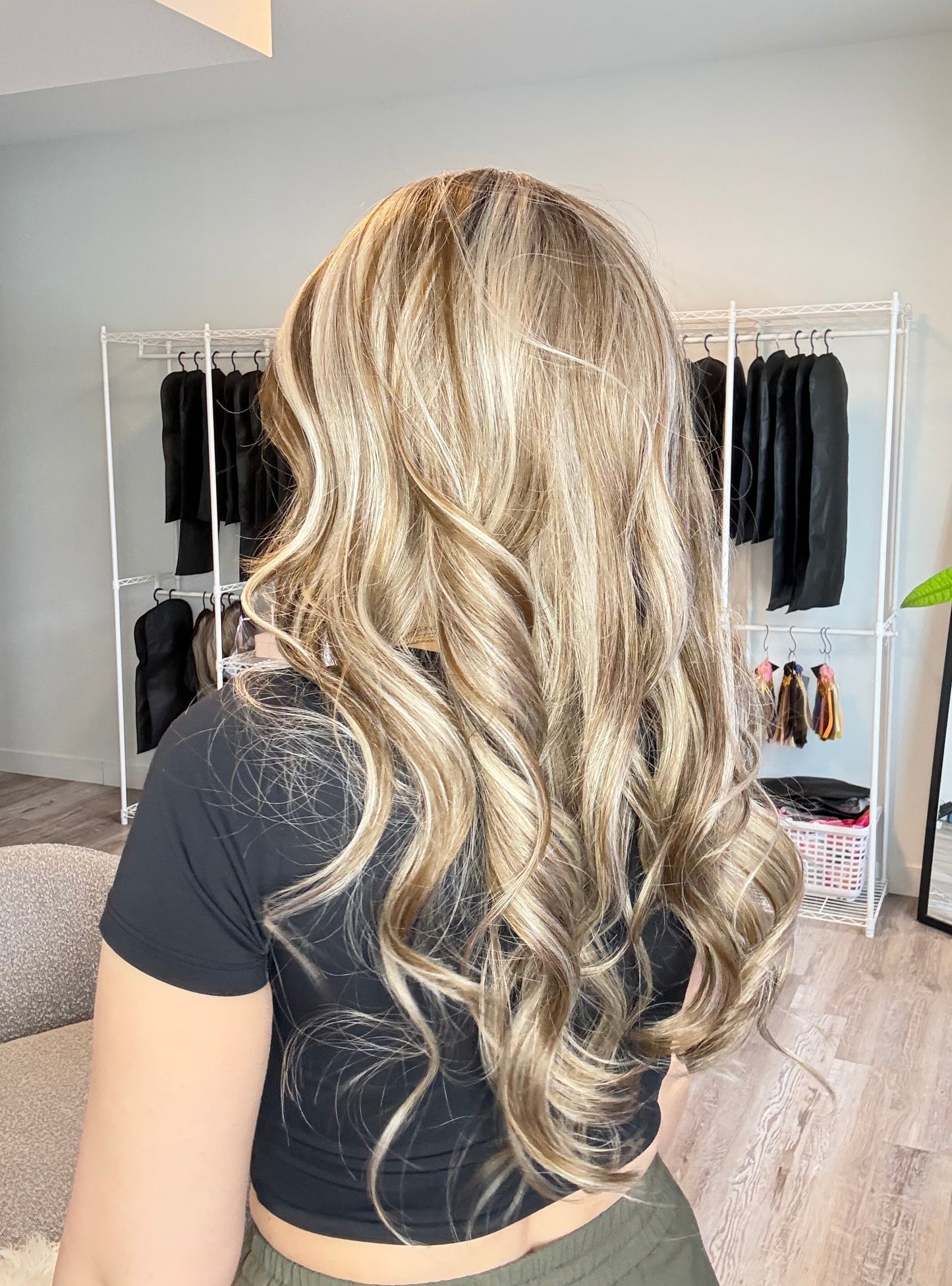 Person with long, wavy blonde hair in a salon setting.