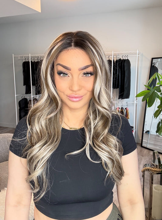 Woman with long, wavy hair in a room with clothing racks and decor.