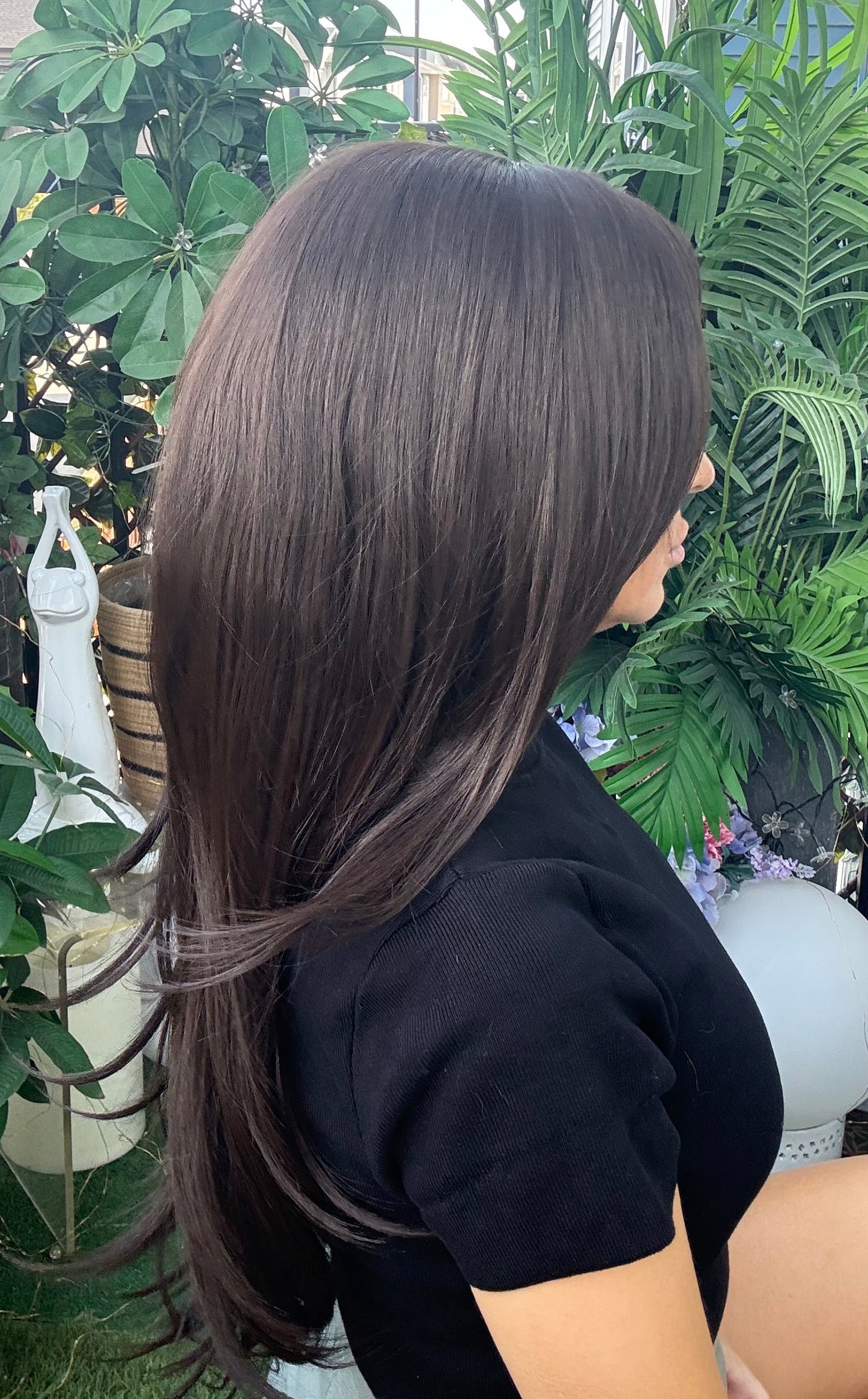 Person with long hair sitting among green plants