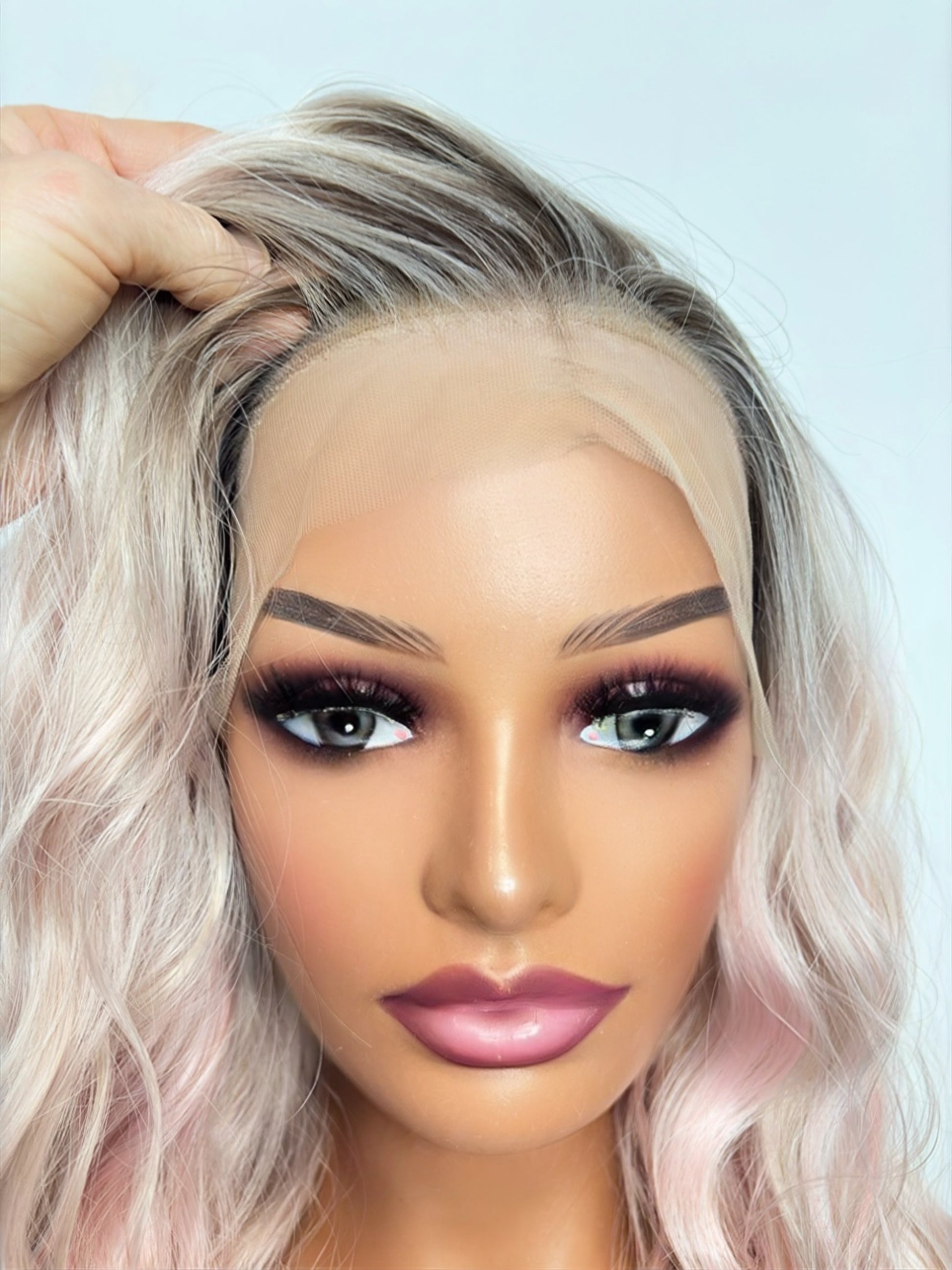 Close-up of a person with blonde hair and makeup on a light blue background