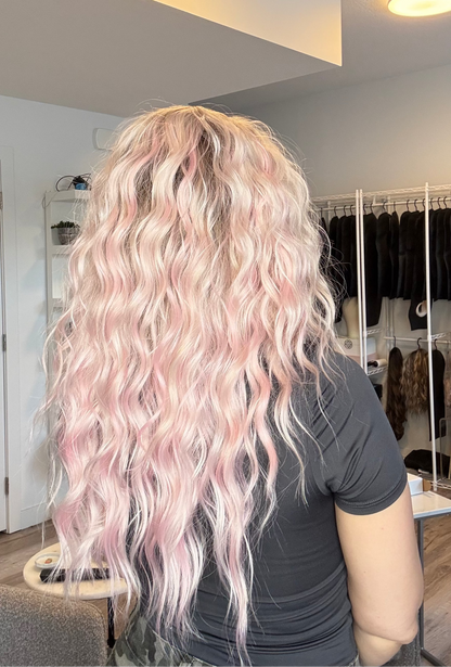 Person with long, wavy, pink hair in a salon setting.