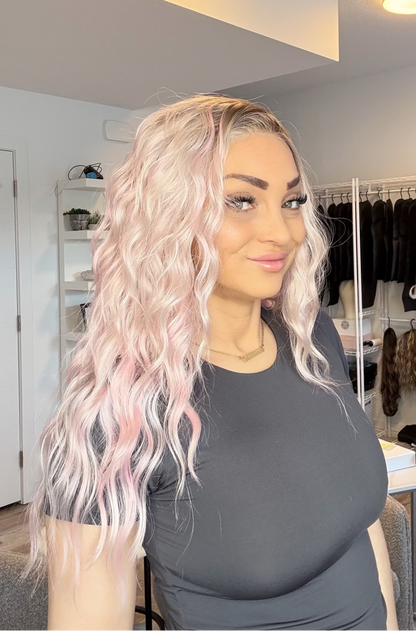 Woman with pink hair in a room with clothing racks and shelves.