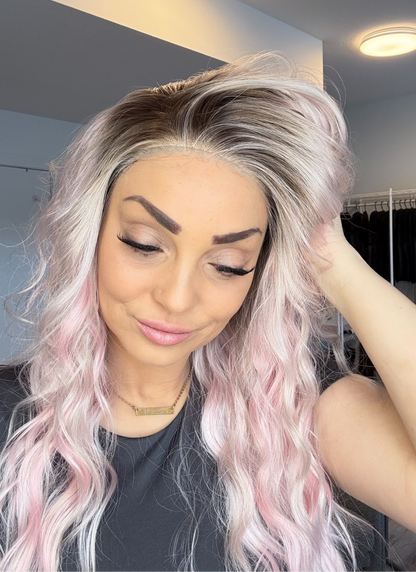 Woman with long, wavy hair in a room with clothing racks in the background