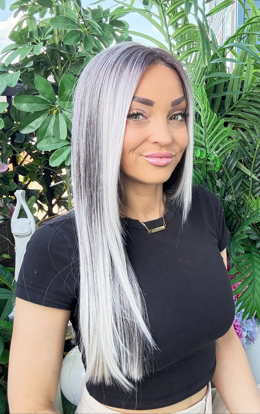 Woman with long silver hair standing in front of green plants