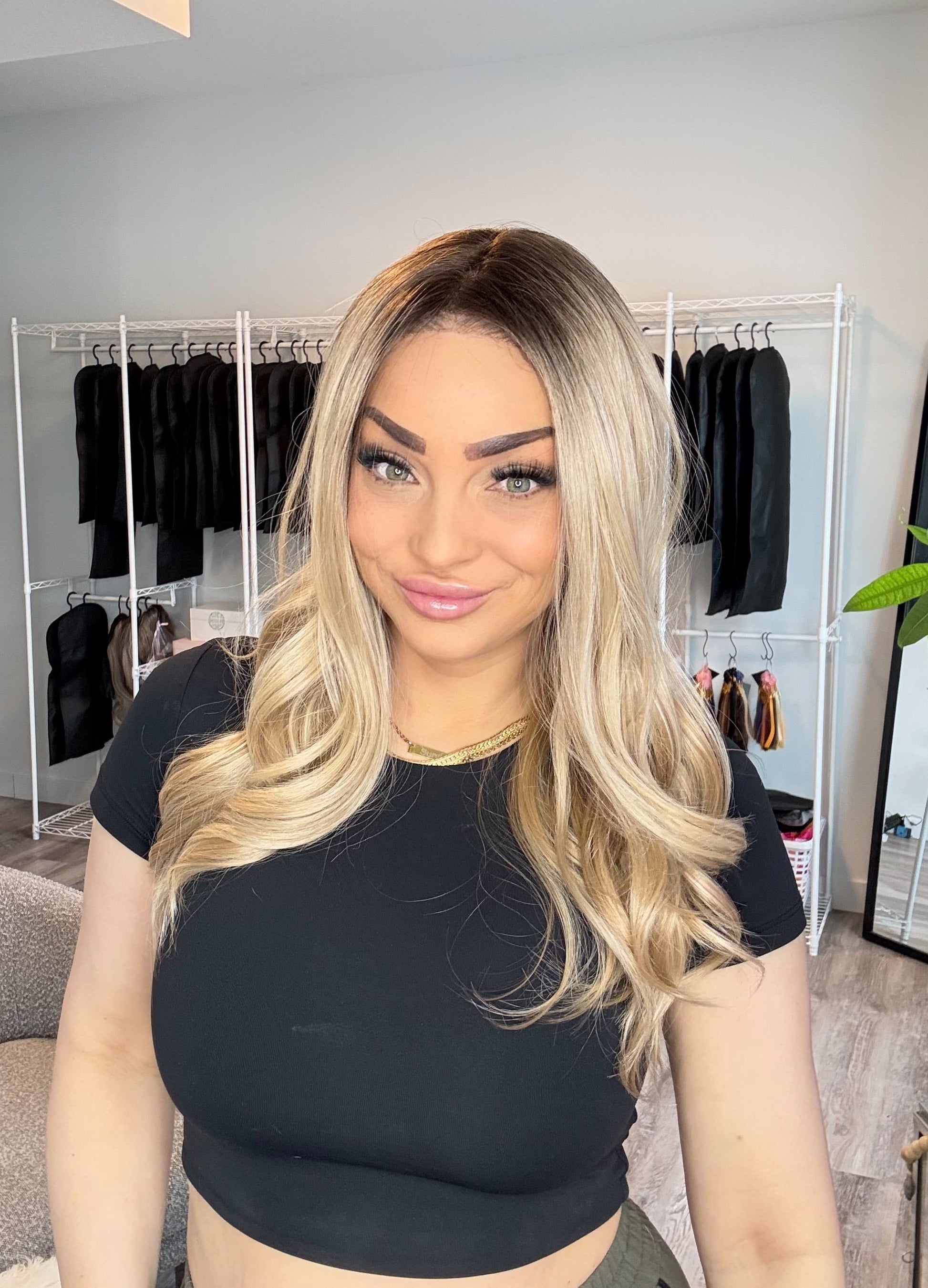 Woman with long blonde hair in a room with clothing racks and decor.