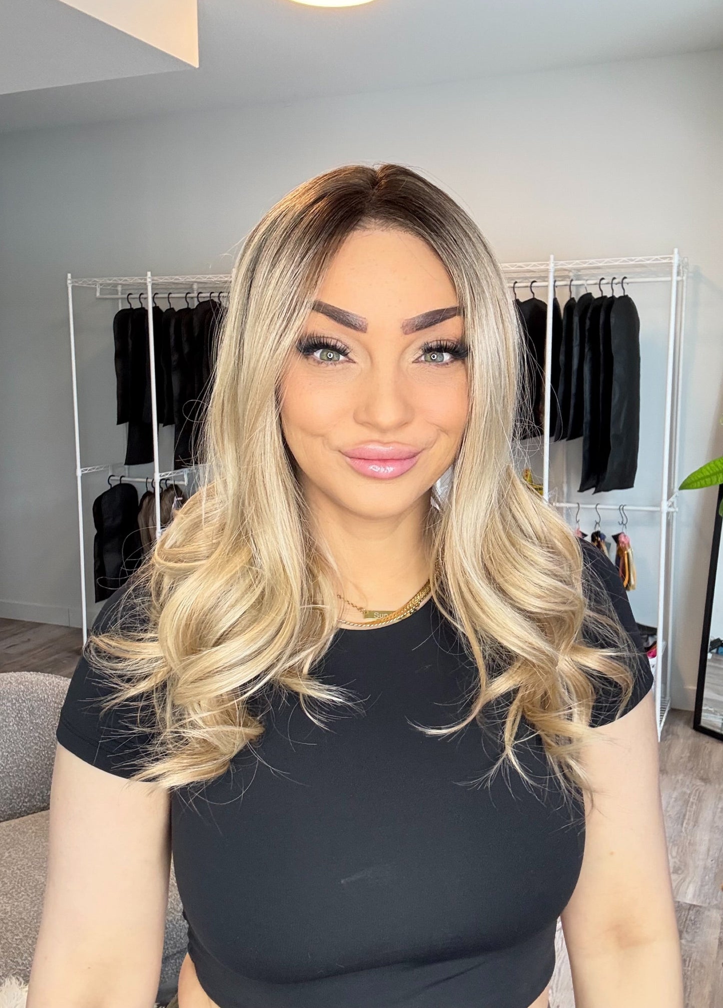 Woman with styled hair in a room with clothing racks and decor.