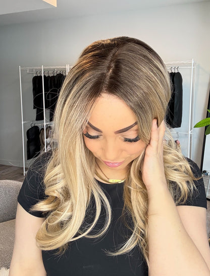 Woman with styled hair in a room with clothing racks and decor.
