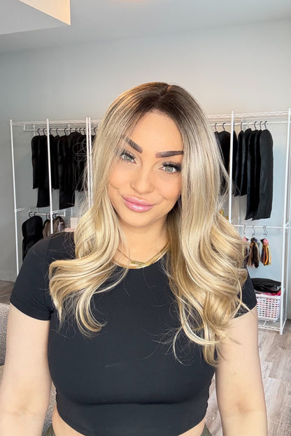 Woman with long blonde hair in a room with clothing racks and decor.
