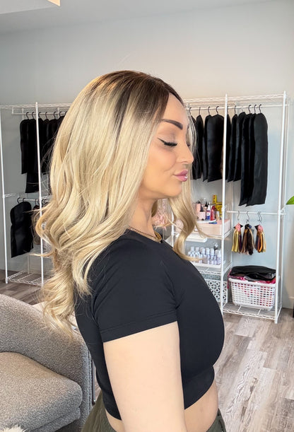 Woman with styled hair in a room with clothing racks and decor.