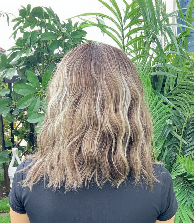 Person with shoulder-length hair in front of a green plant background