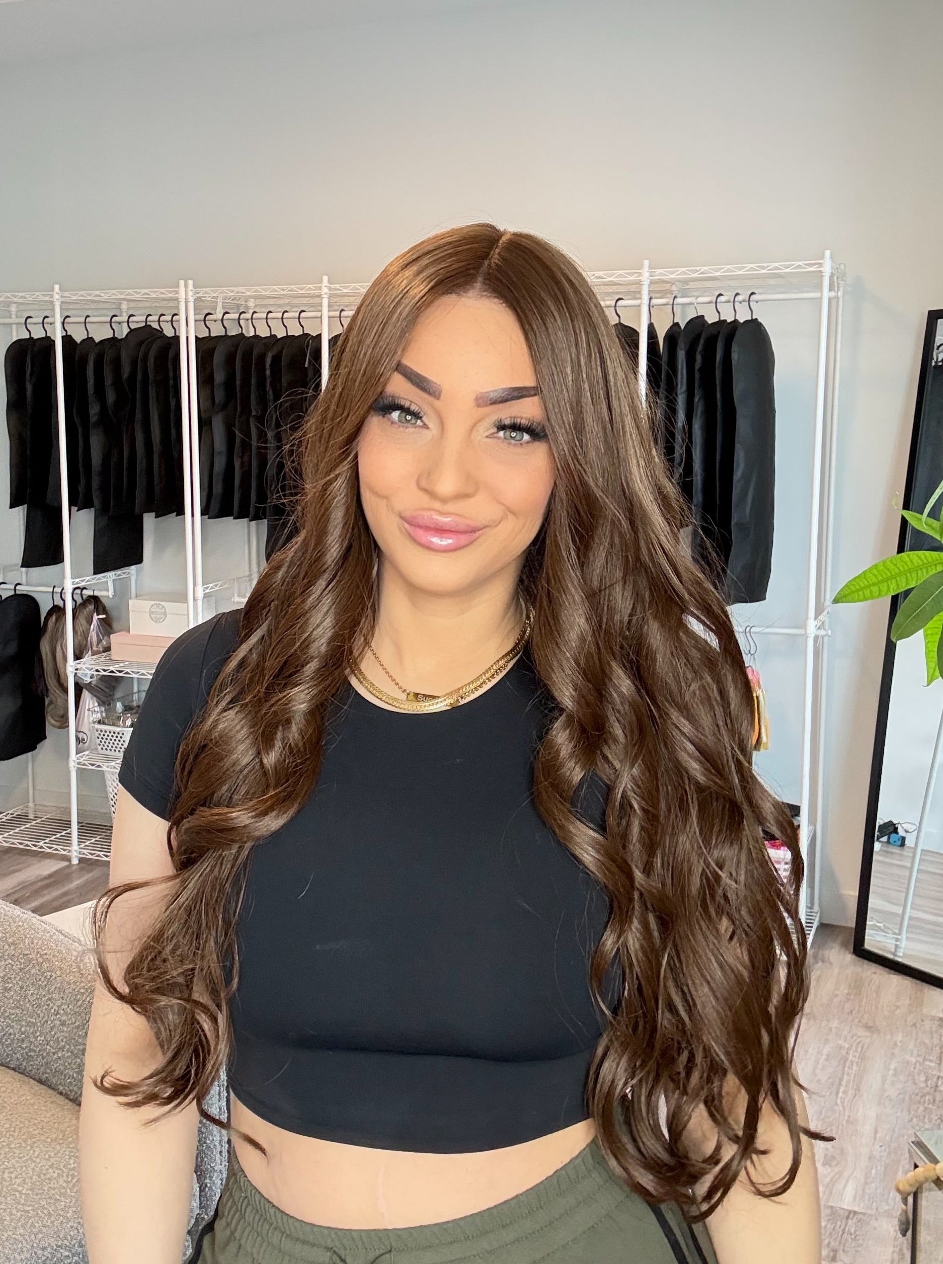 Woman with long brown hair in a room with clothing racks and decor.