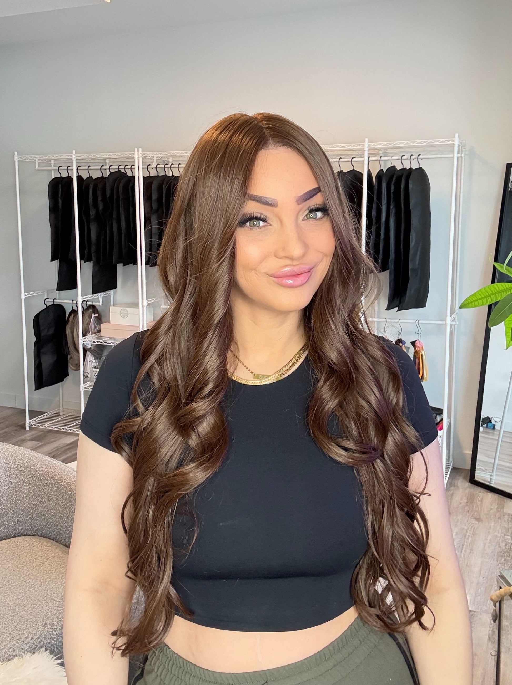 Woman with long, wavy hair in a room with clothing racks and decor.