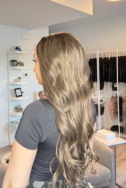 Person with long blonde hair looking into a mirror in a store setting.