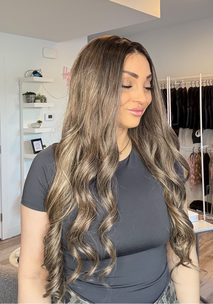 Woman with long, wavy hair in a room with shelves and clothing racks.