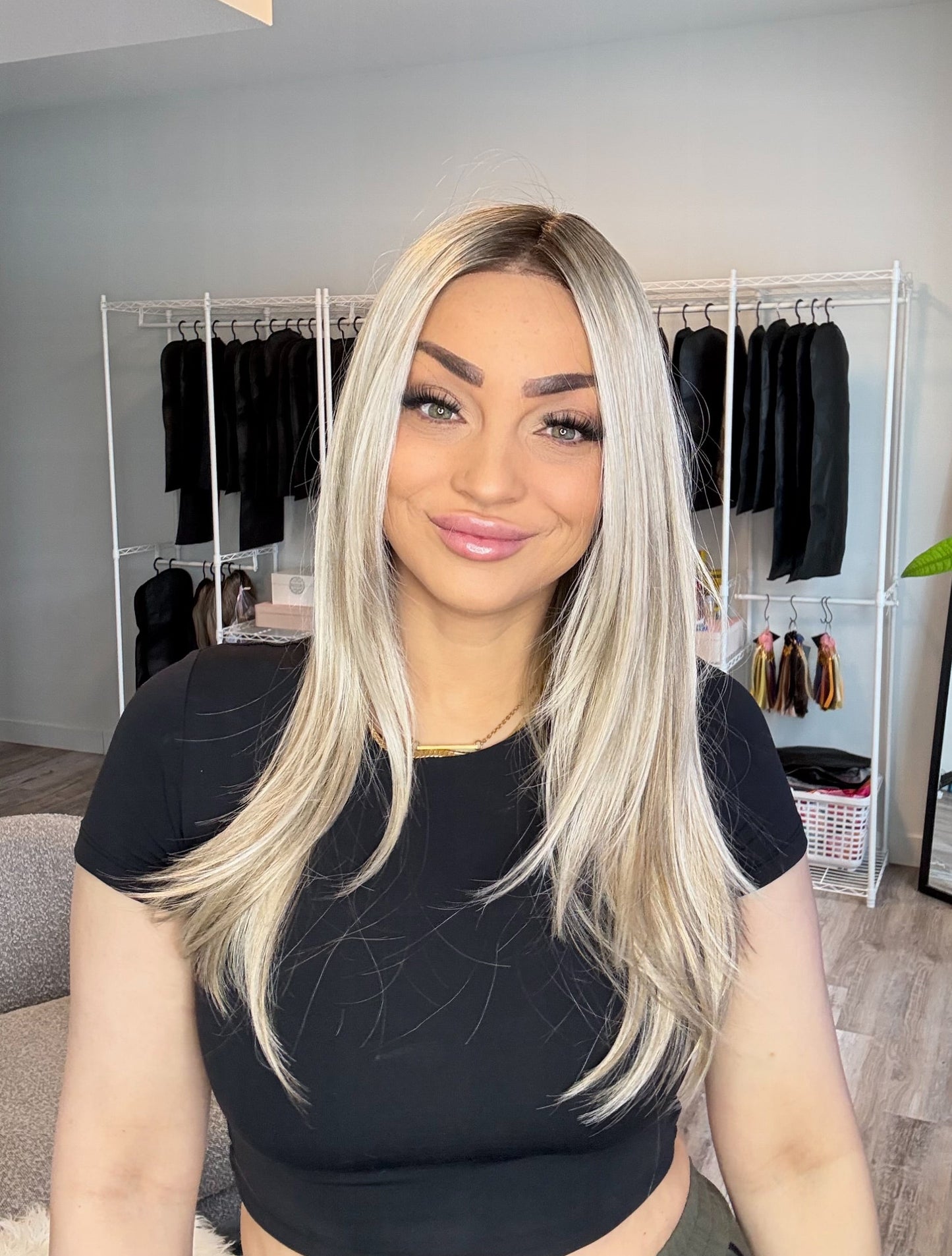Woman with long blonde hair in a room with clothing racks and decor.