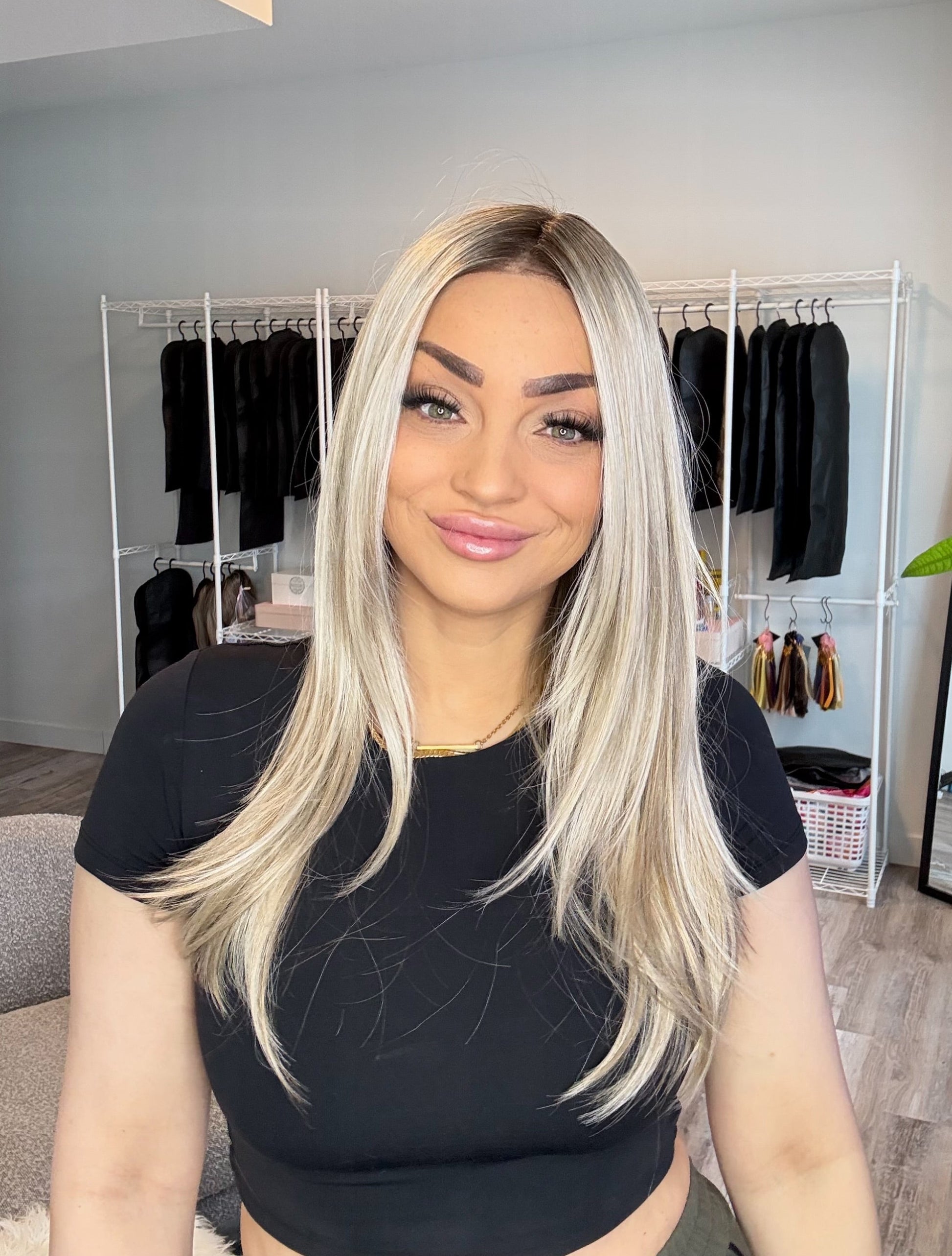 Woman with long blonde hair in a room with clothing racks and decor.