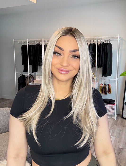 Woman with long blonde hair in a room with clothing racks and decor.