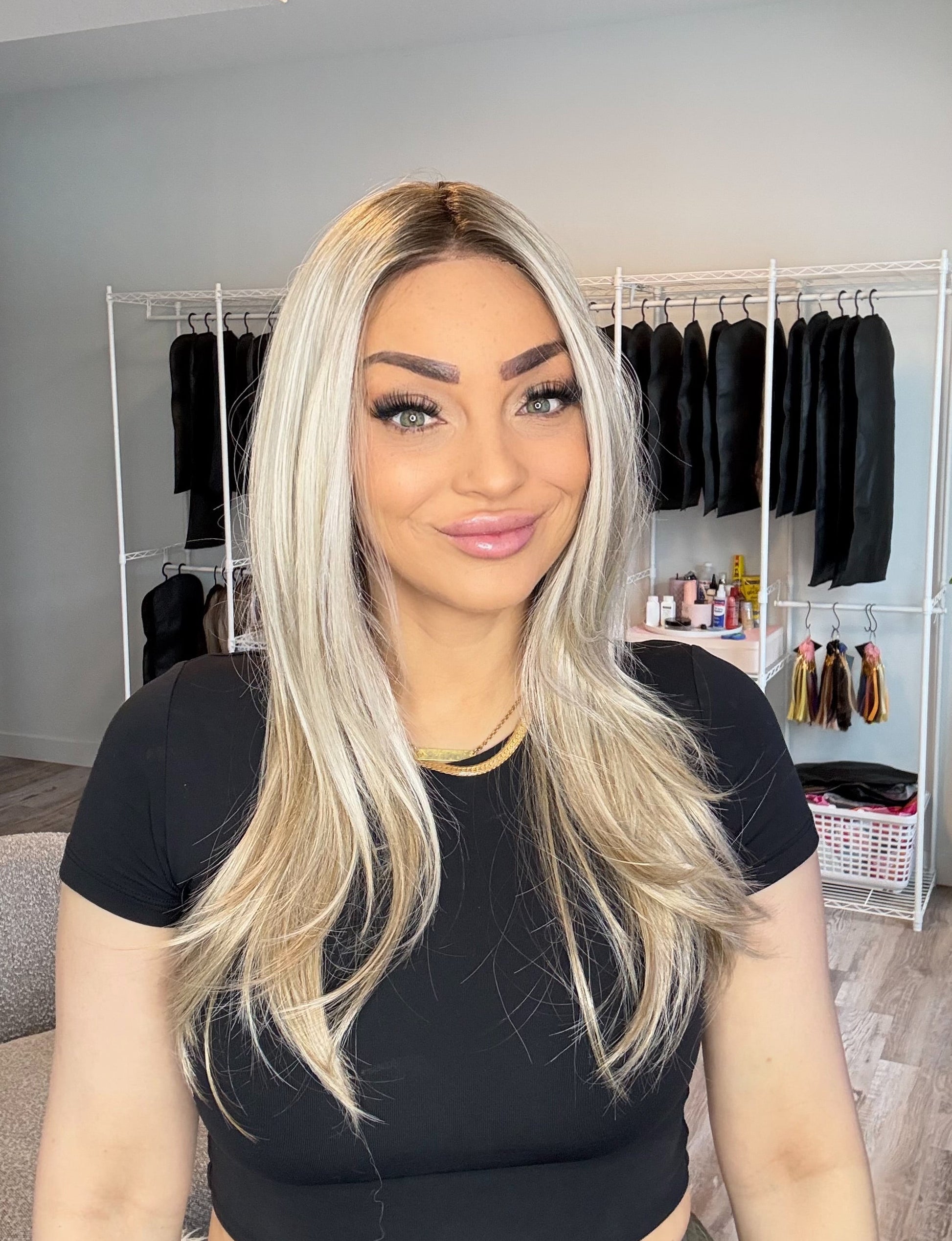 Woman with long blonde hair in a room with clothing racks and decor.
