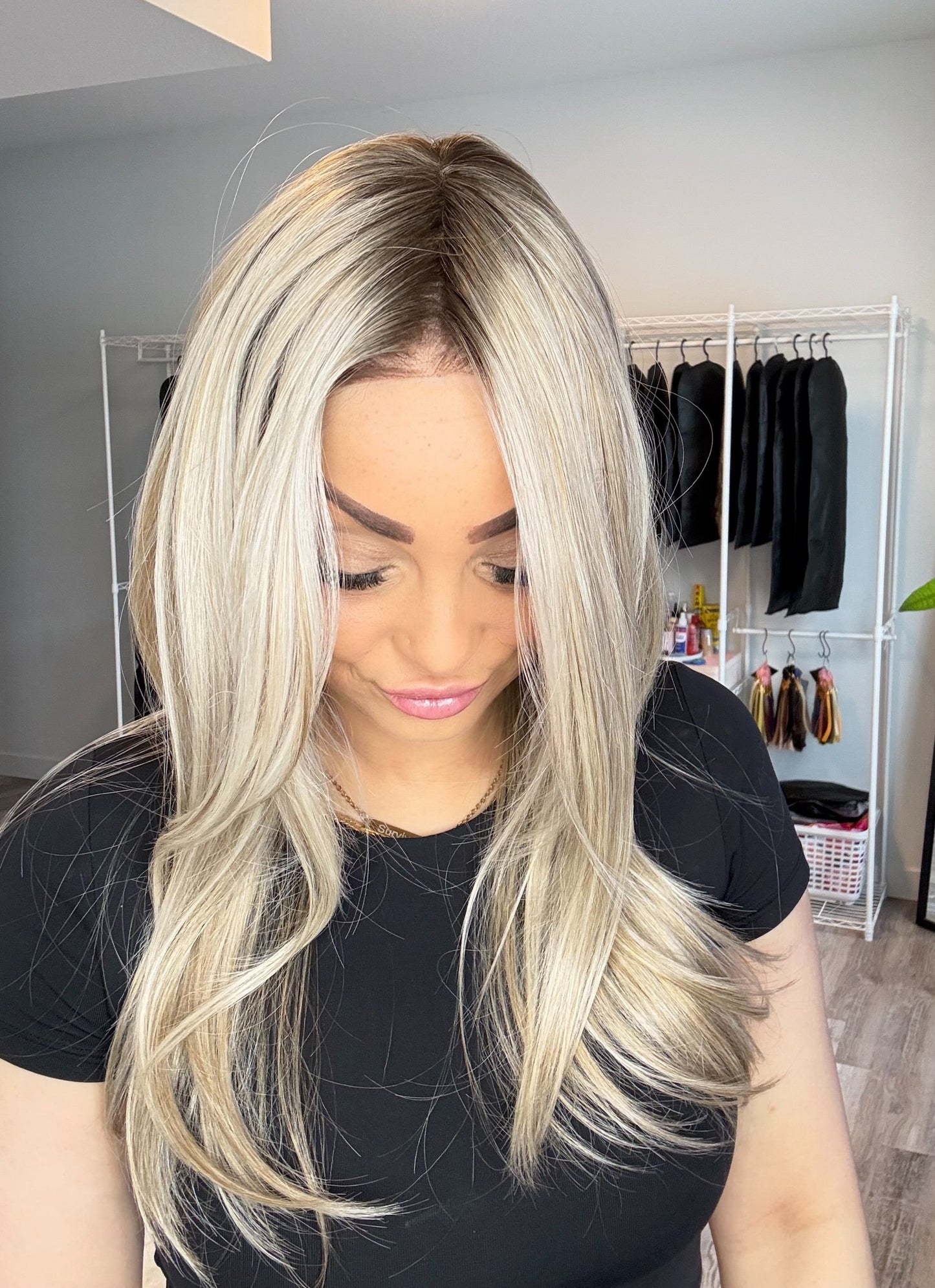 Woman with long blonde hair in a room with clothing racks and decor.