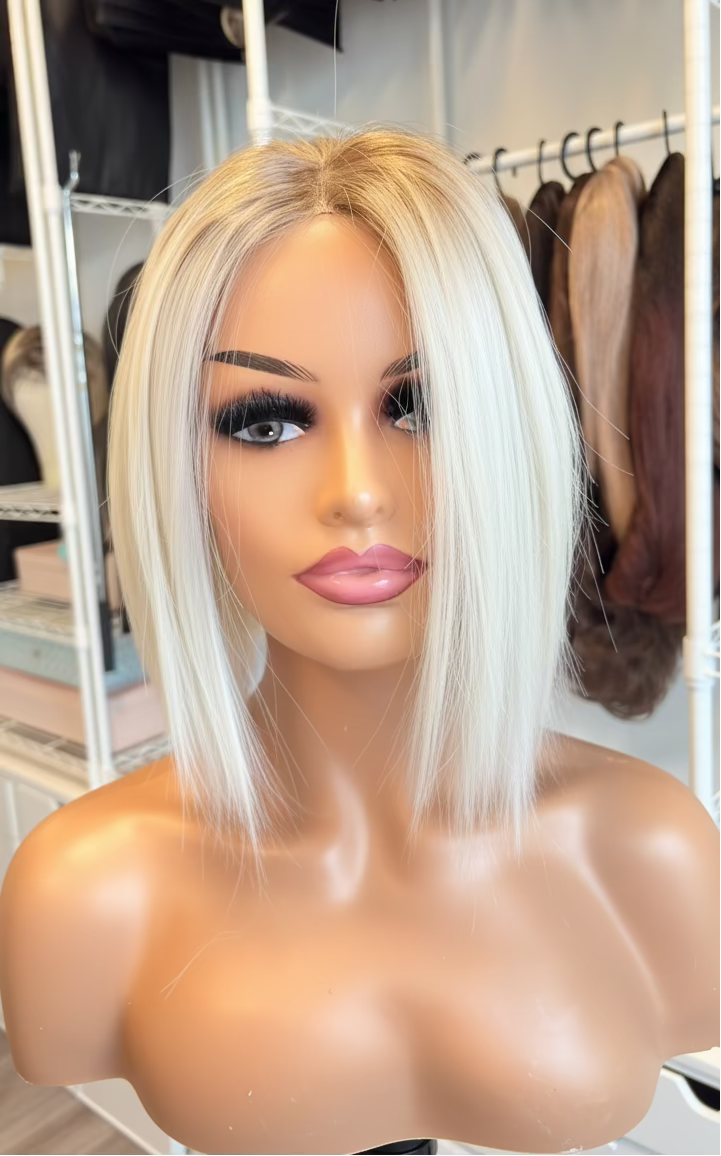 Blonde wig on a mannequin head with a blurred background of a store setting.