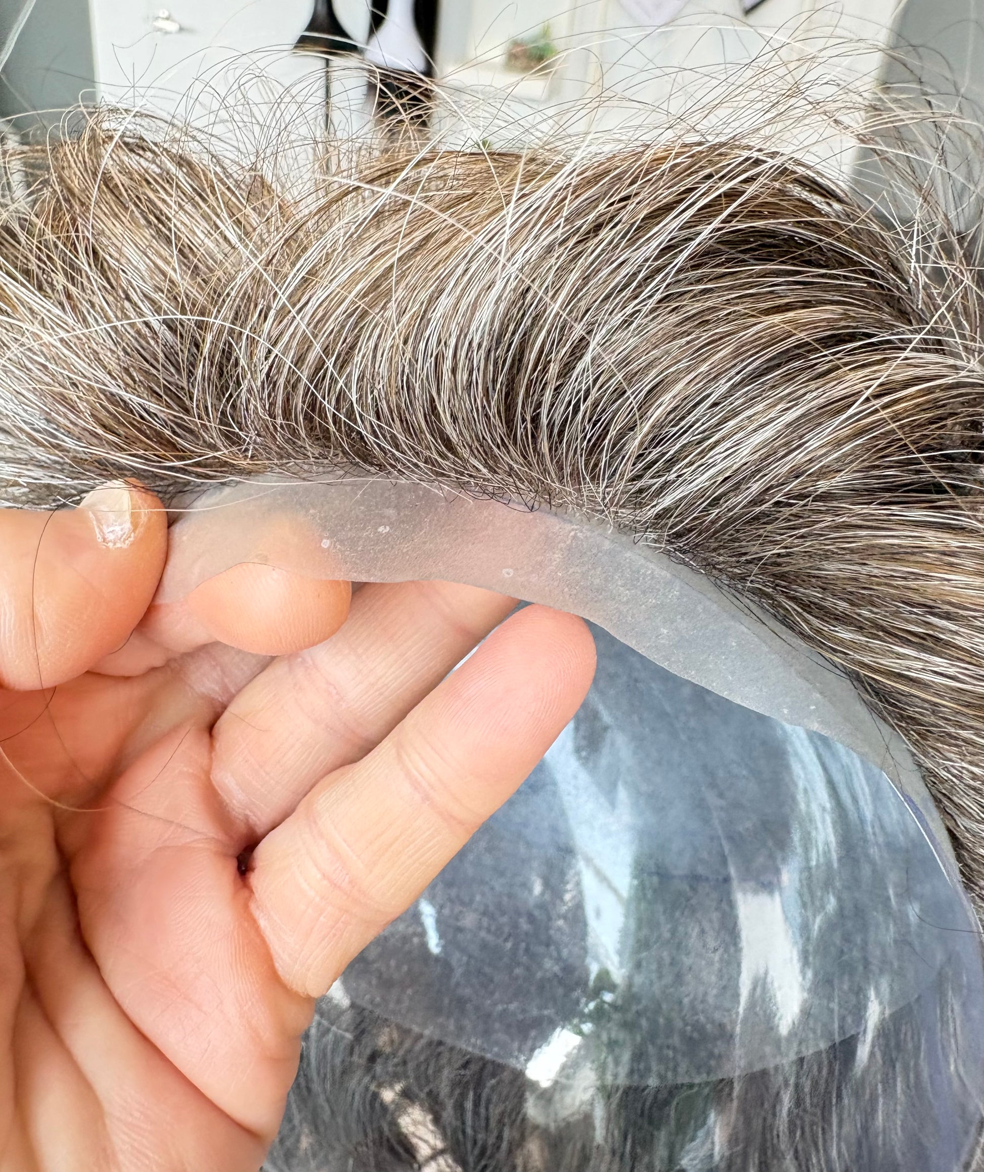 Close-up of a hairpiece held by a hand with a blurred background